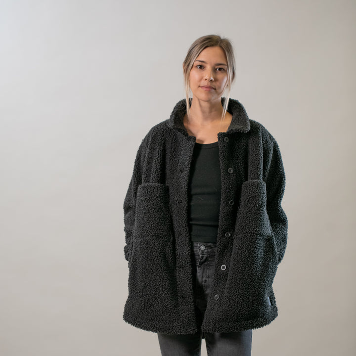 A person stands against a plain light background, wearing an oversized Women&