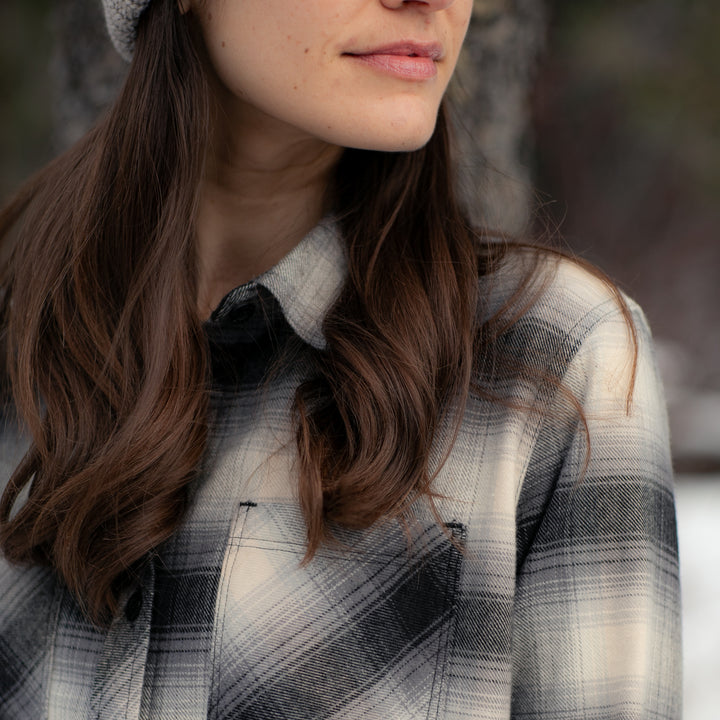 A woman with long brown hair enjoys the outdoors in a forest, wearing the Women&
