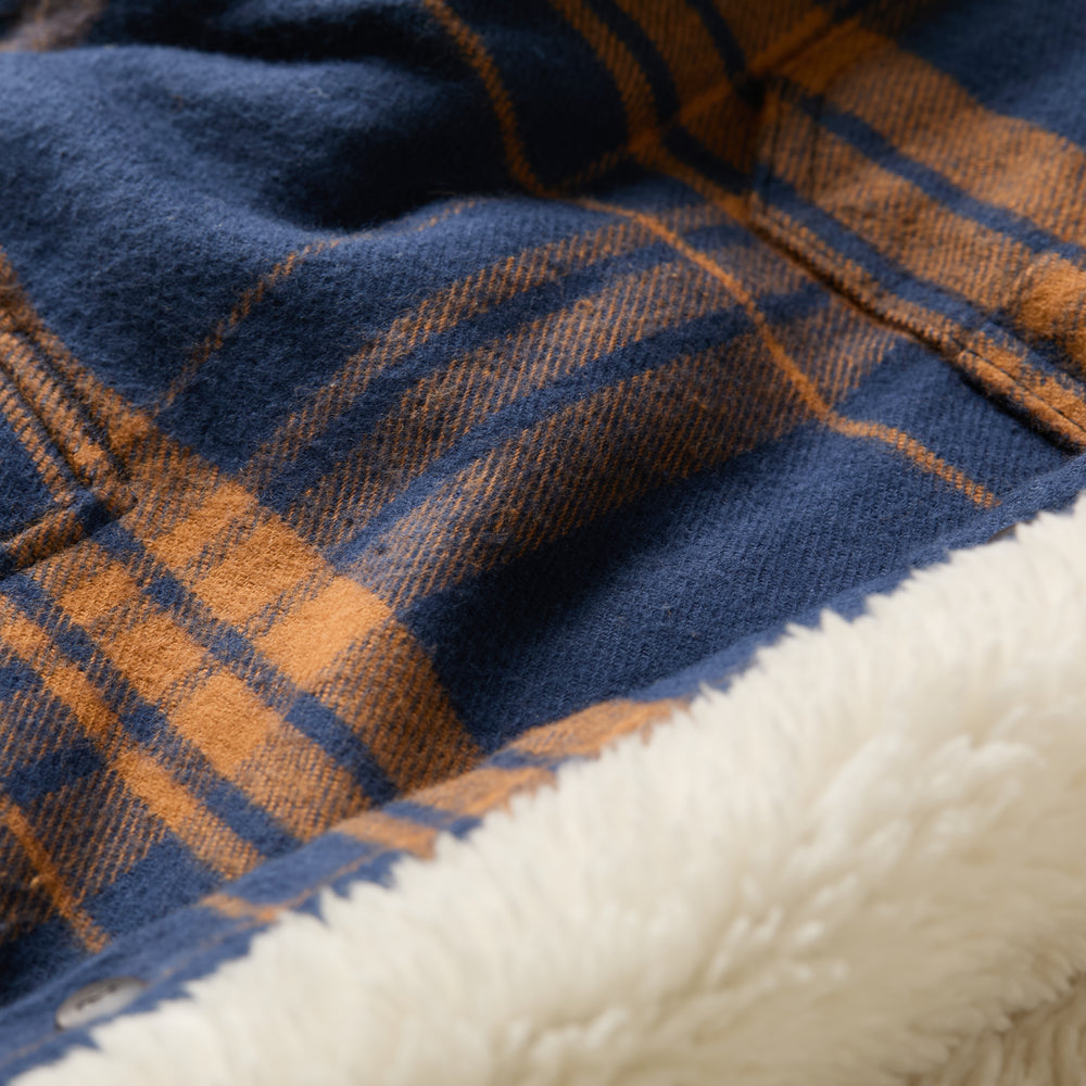 Close-up of the Men's Northwood Sherpa Insulated Flannel Jacket in Bison Blue, featuring soft blue and orange plaid with a cream sherpa lining for warmth and comfort.