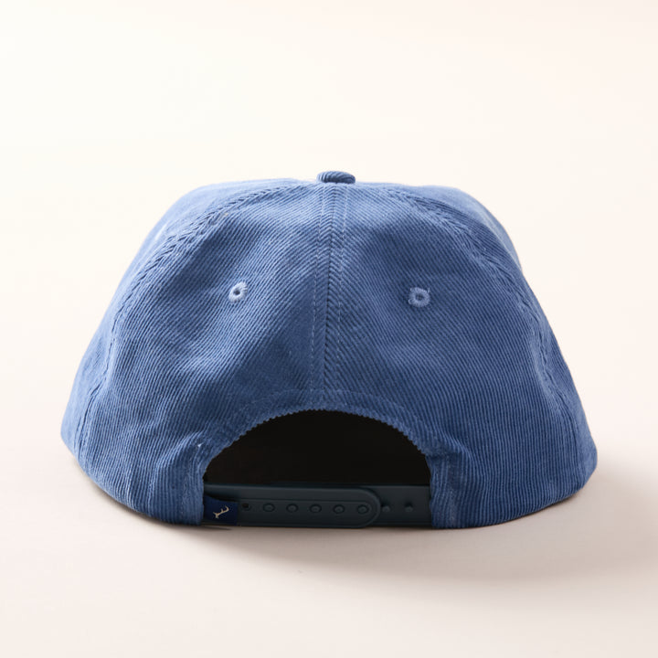 The Pladra Quail Corduroy Hat- Blue, shown from the back, features cotton corduroy and an adjustable fit strap.