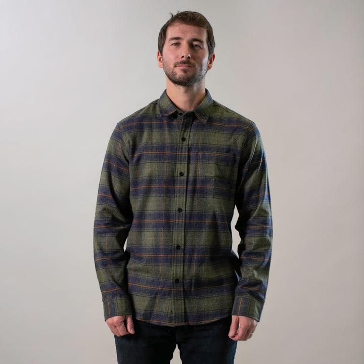 A man stands against a plain light background, wearing the Men&