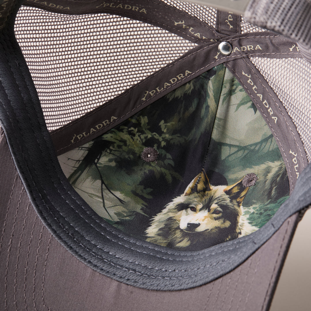 Close-up of the Mountain Trucker Hat- Charcoal Grey interior, showcasing a wolf-in-forest image on the front panel, PLADRA branding along the seams, and an adjustable snap back for comfort.