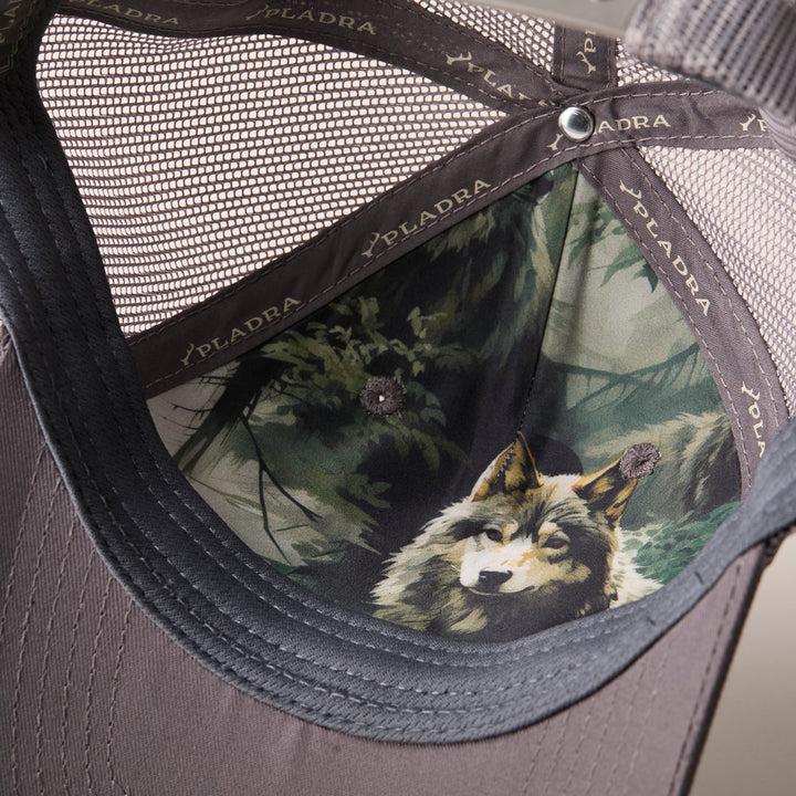 Close-up of the Mountain Trucker Hat- Charcoal Grey interior, showcasing a wolf-in-forest image on the front panel, PLADRA branding along the seams, and an adjustable snap back for comfort.