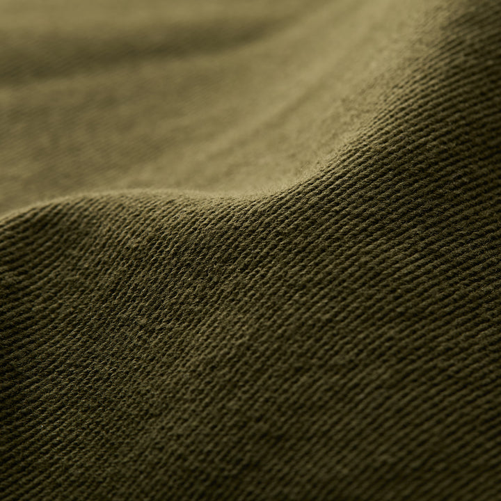 Close-up of hunter green, ribbed fabric with gentle folds, featured on Pladra&