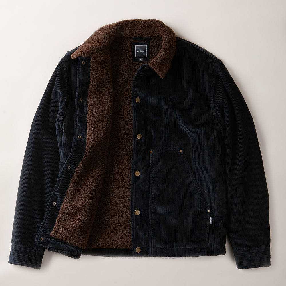 The Men's Ironwood Sherpa Jacket in Midnight Blue features a soft brown sherpa lining, metal snap buttons, collar, side pockets, and cozy textured interior for warmth. Shown unbuttoned to display the plush cotton corduroy design.