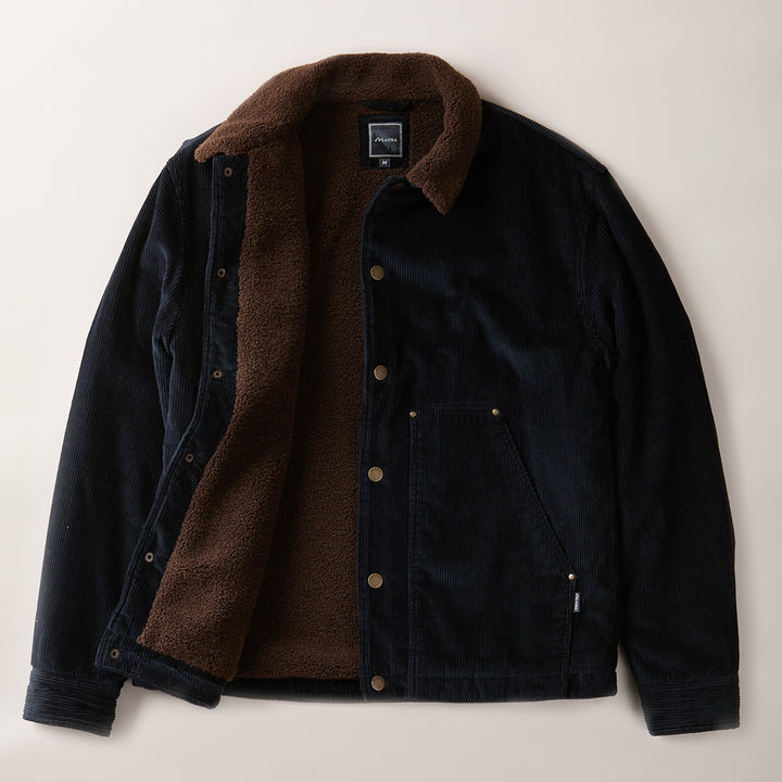 The Men's Ironwood Sherpa Jacket in Midnight Blue features a soft brown sherpa lining, metal snap buttons, collar, side pockets, and cozy textured interior for warmth. Shown unbuttoned to display the plush cotton corduroy design.
