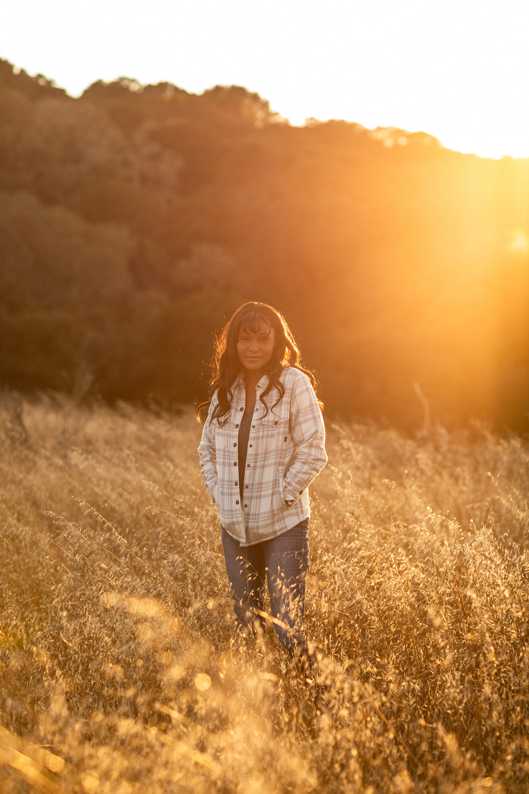 A woman stands in a sunlit field wearing the Pladra Women&