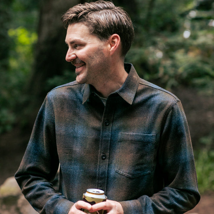 Man with brown hair smiles holding a canned drink in Pladra&