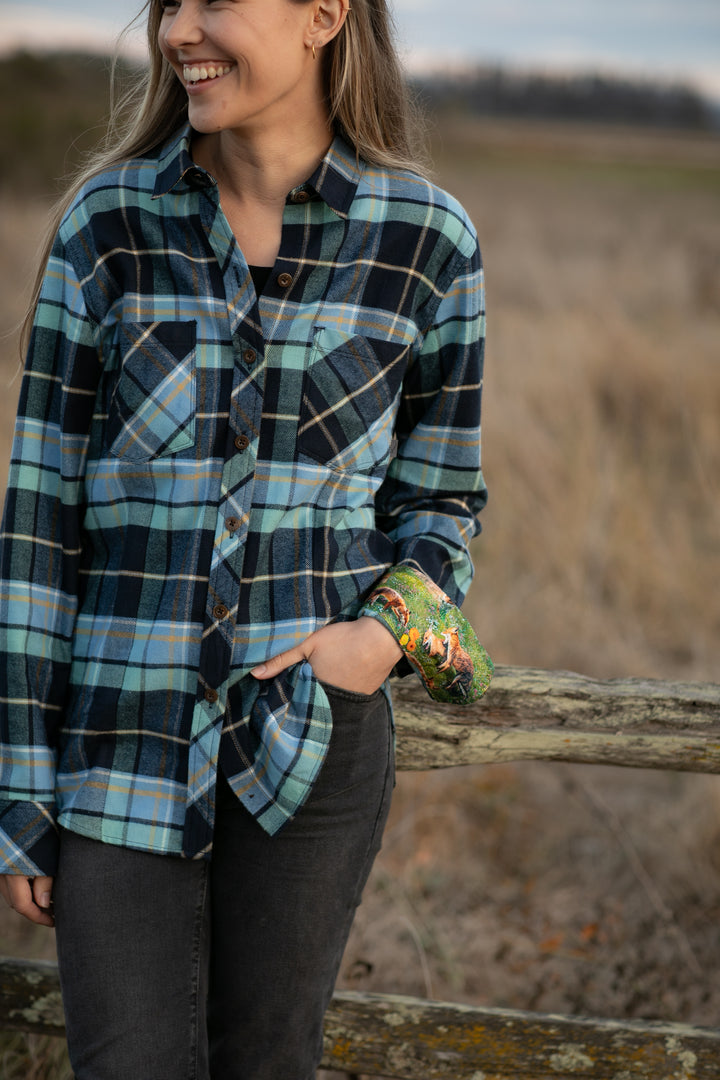 A woman stands outdoors by a wooden fence, smiling, in the Women&