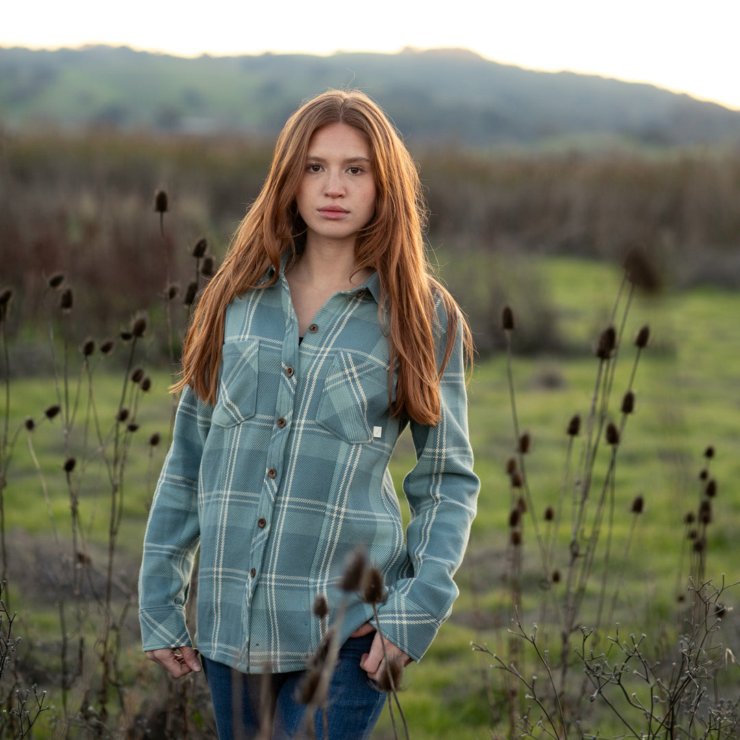A young woman with long red hair, wearing the Women&