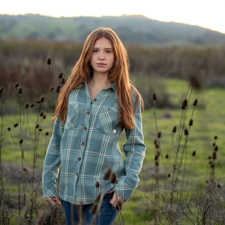 A young woman with long red hair, wearing the Women&