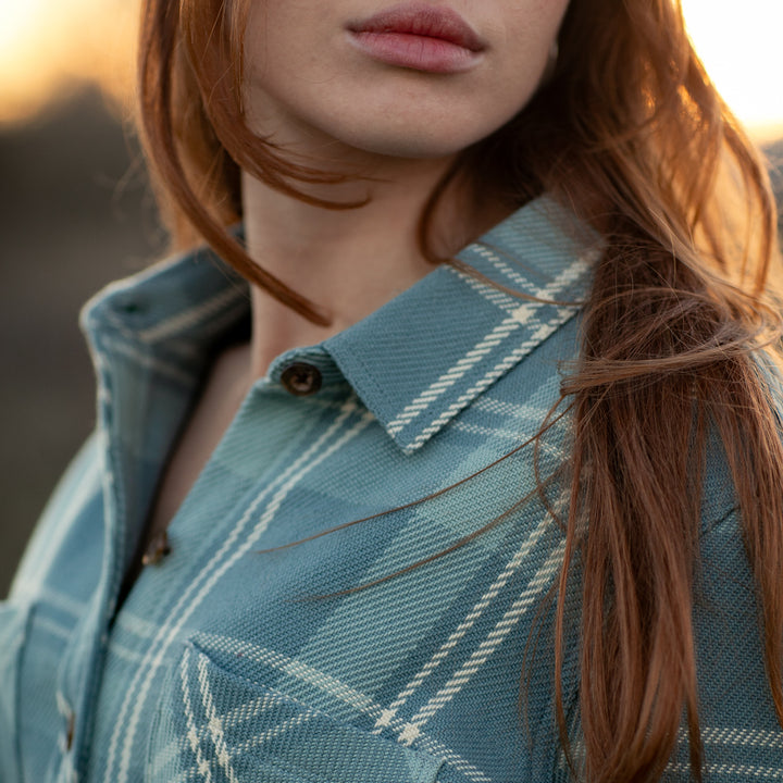 A close-up of a woman with long red hair wearing the Women&