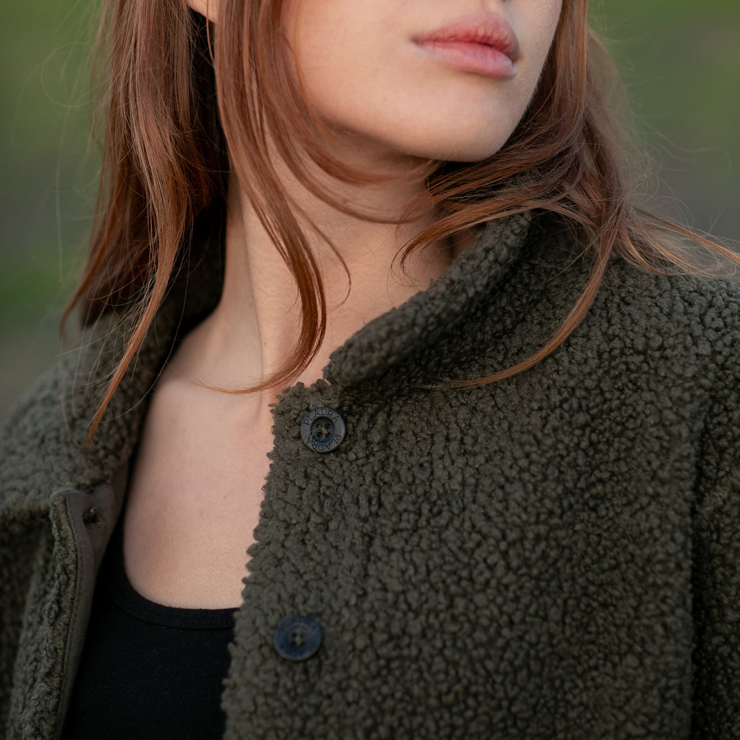 Woman with long hair in Pladra Women's Headlands Sherpa Shacket - Forest Green, face partially visible, shoulders up.