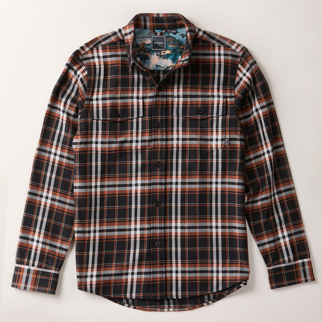 The Men's Workhorse Elite Flannel Shirt - Posey Black is a heavyweight Portuguese flannel with a plaid pattern in black, white, orange, and blue. It features long sleeves, two chest pockets, and a classic collar. Laid flat on a light surface.