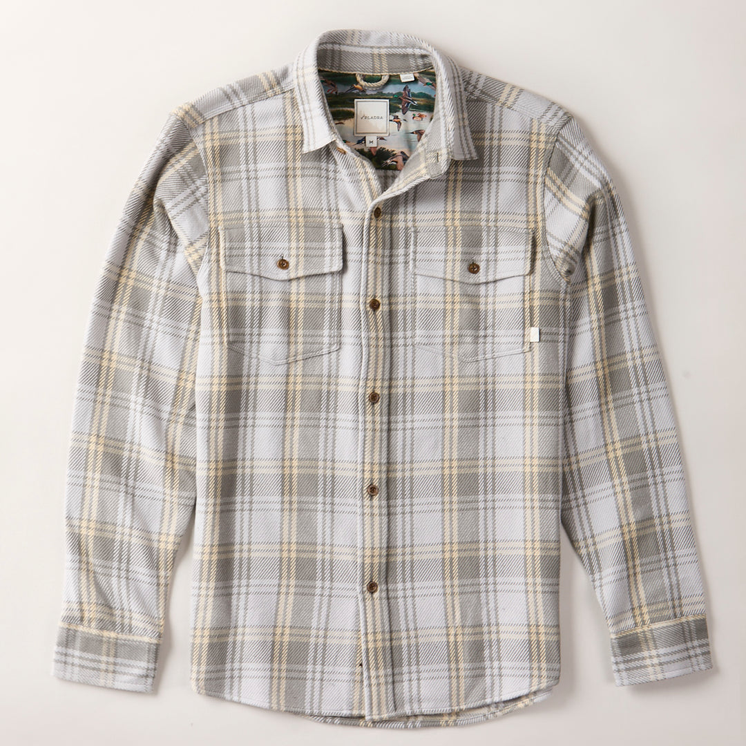 The Men's Fireside Flannel - Quartz Grey is a long-sleeve, button-up plaid shirt in gray, beige, and white with two chest pockets and brown buttons, made from soft organic cotton flannel and photographed flat on a white background.