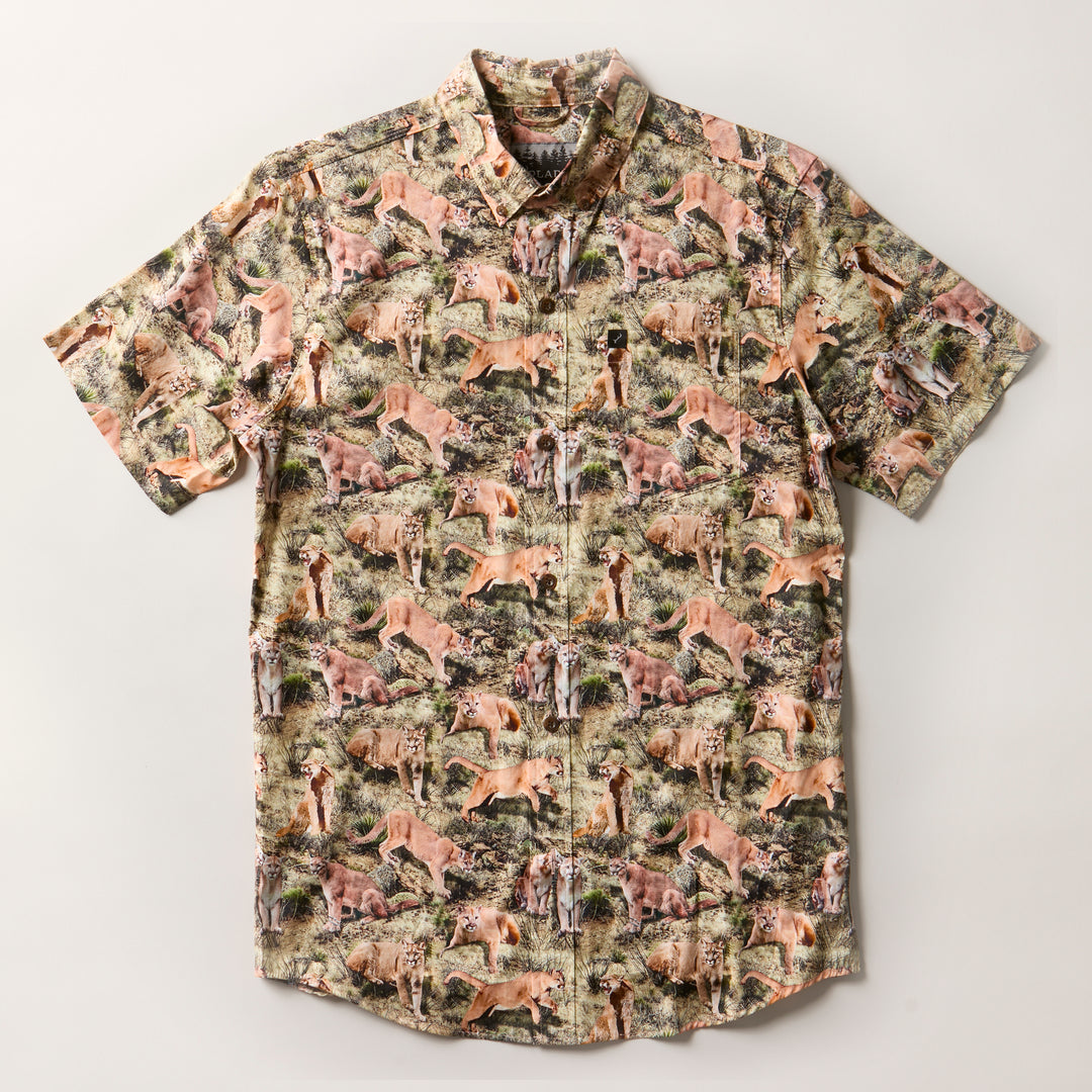 Men's S/S Printed Outdoor Aloha Shirt - Mountain Lions: A short-sleeve button-up with a savanna-inspired all-over print of mountain lions, giraffes, cheetahs, and zebras. Made from 100% cotton and displayed flat on a white background.