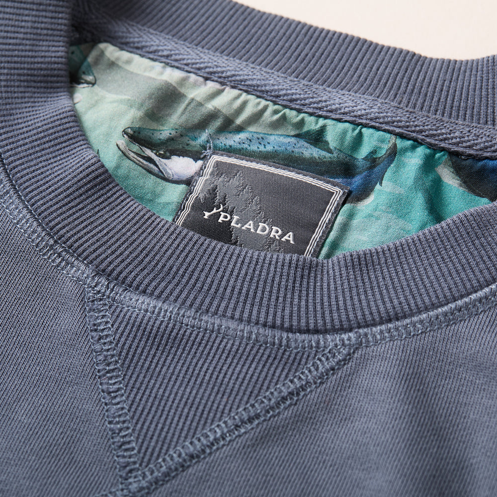 Close-up of Pladra Men's Klamath Crew in Stone Blue, classic fit pullover with fish-patterned lining and brand label.