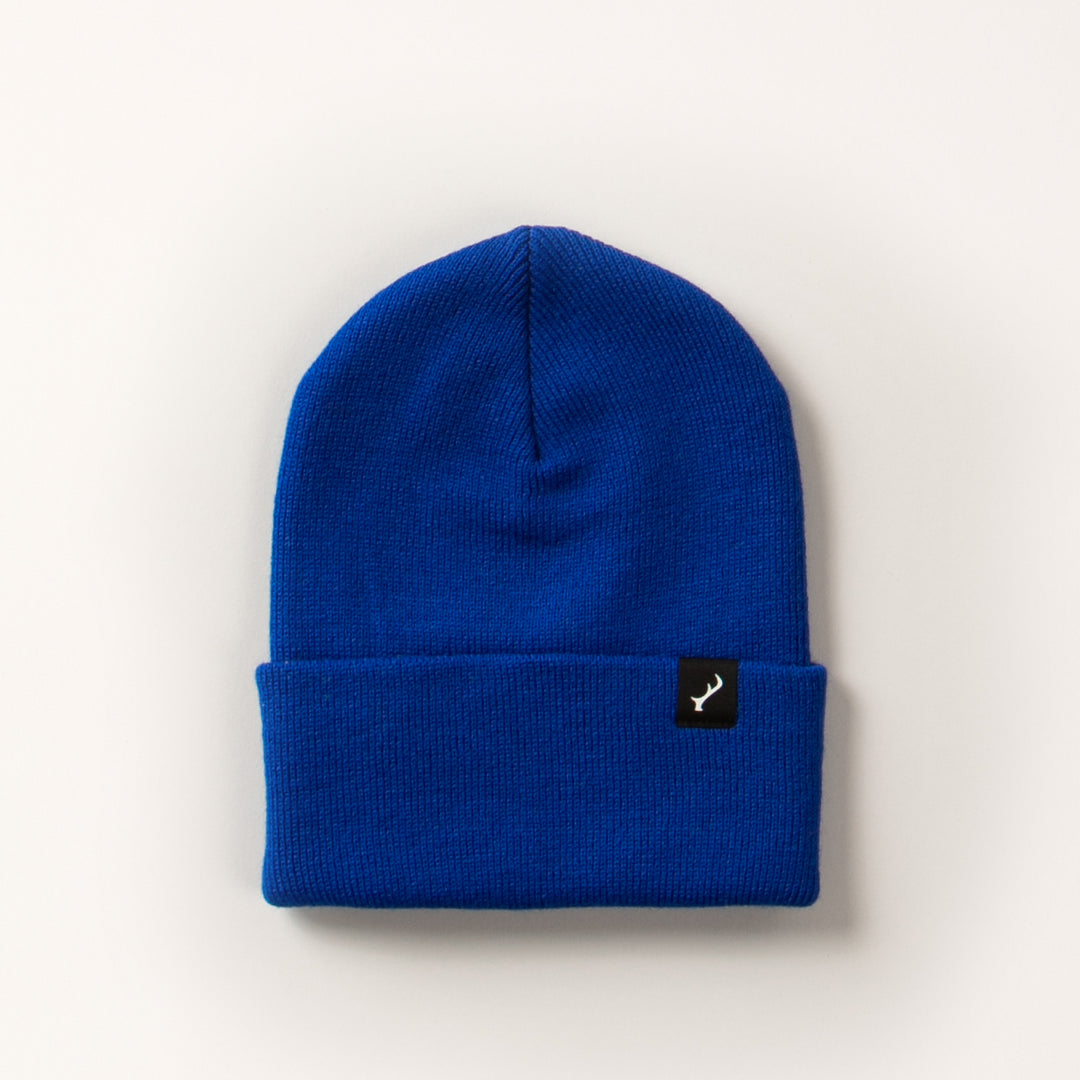 Pladra Stretch Cuff Beanie in royal blue with folded brim and black tag featuring a white antler logo.