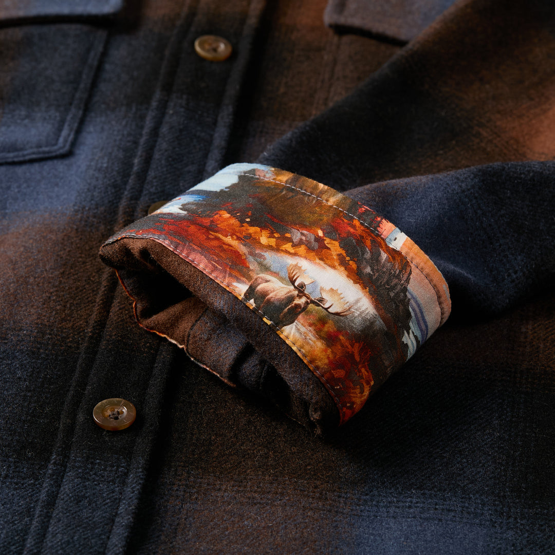 Pladra Men's Workhorse Wool Flannel Shirt in Tundra Brown features rolled cuffs with a forest and moose scene inside.
