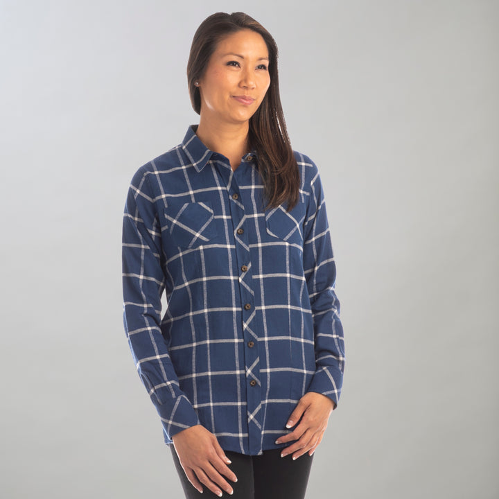 A woman with long, straight brown hair stands against a light gray background, gently smiling as she wears the Women&