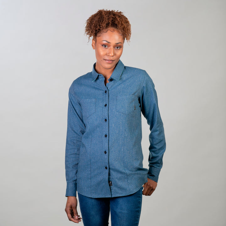 A woman with curly hair stands against a plain background, wearing the Women&