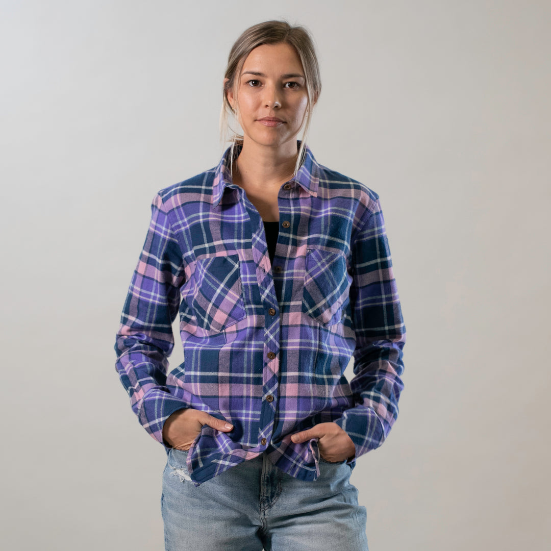 A woman wears the Pladra Women's Every Day Flannel Shirt in Blackberry Purple with jeans, hands in pockets.