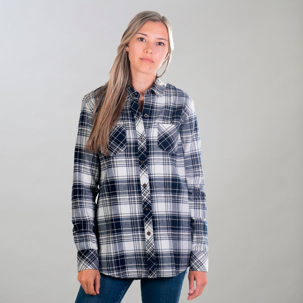 A woman in Pladra's Women's Every Day Flannel Shirt - Butte Blue and blue jeans stands with her long hair loose.