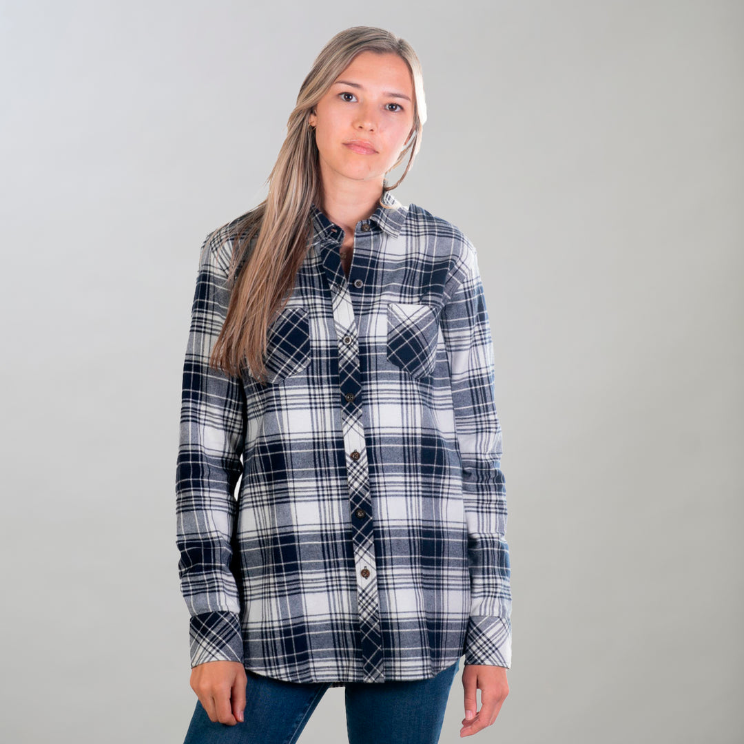 A woman in Pladra's Women's Every Day Flannel Shirt - Butte Blue and blue jeans stands with her long hair loose.