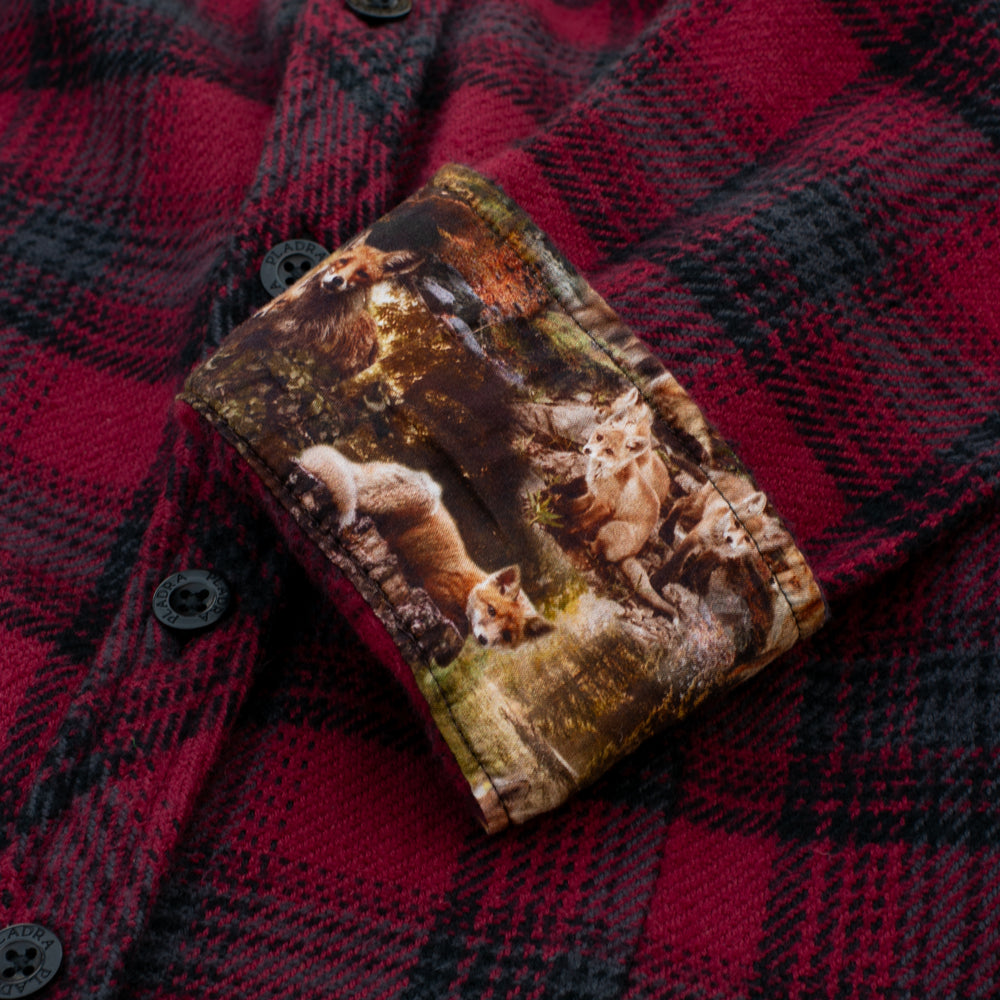 A close-up of the Women's Fireside Flannel-Deadwood Red shows its turned-up cuff, revealing a fox-and-forest print. Made from heavyweight Portuguese flannel, this shirt offers lasting warmth and comfort.
