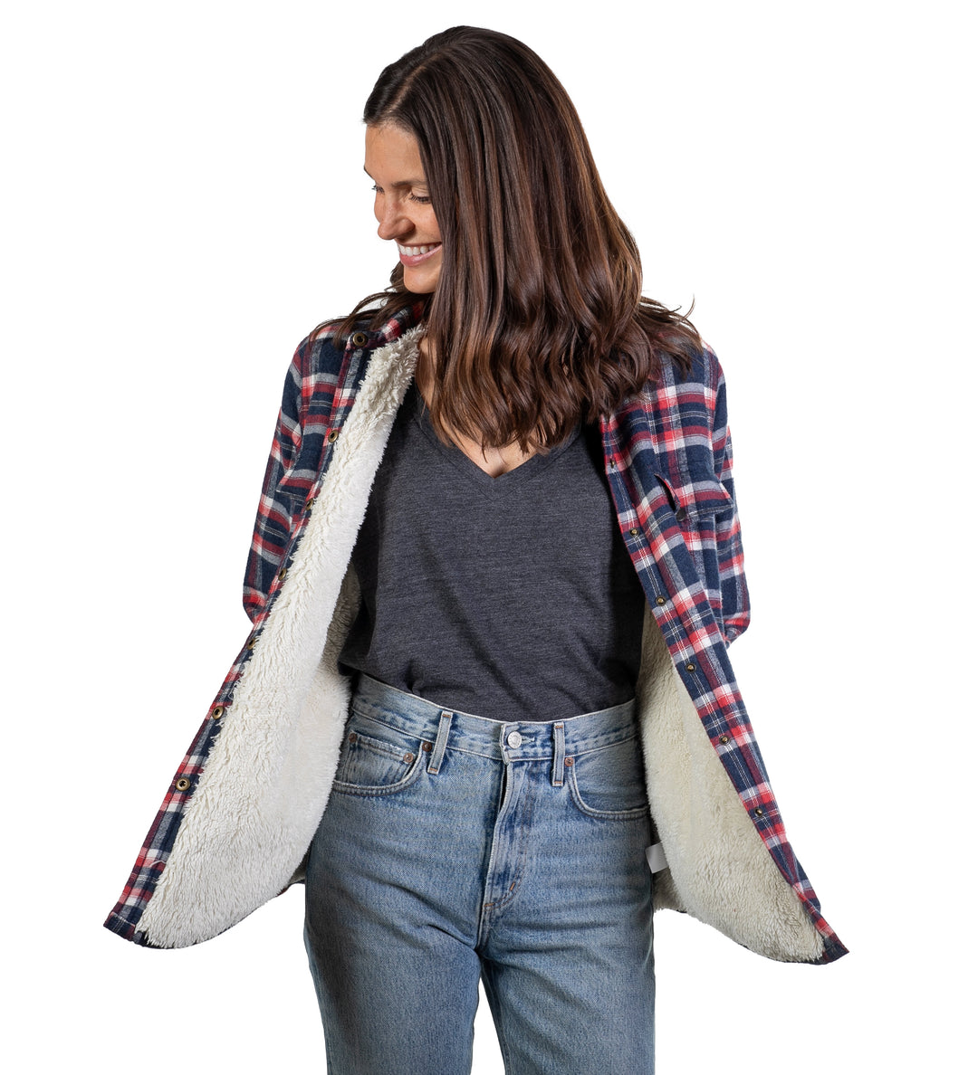 A woman smiles, looking down to her left, wearing blue jeans and the Women&