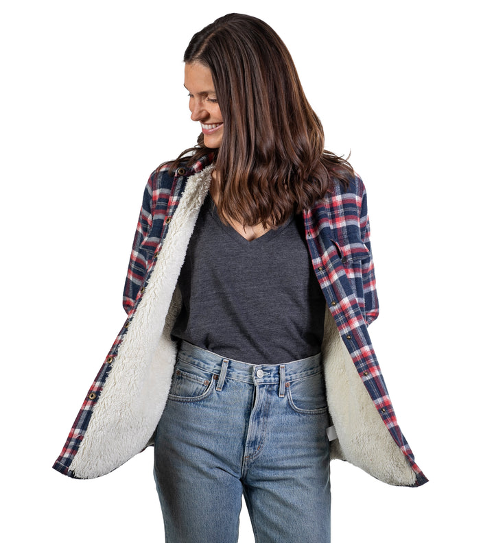 A woman smiles, looking down to her left, wearing blue jeans and the Women&