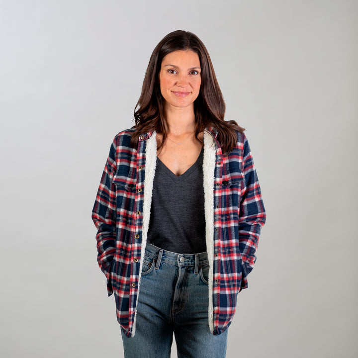 A woman with long brown hair stands against a plain background, wearing the Women&