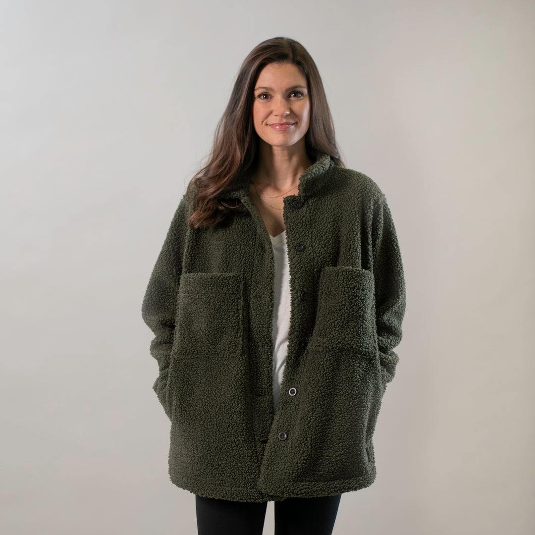 Woman wearing Pladra's Women's Headlands Sherpa Shacket in Forest Green, standing and smiling at the camera.