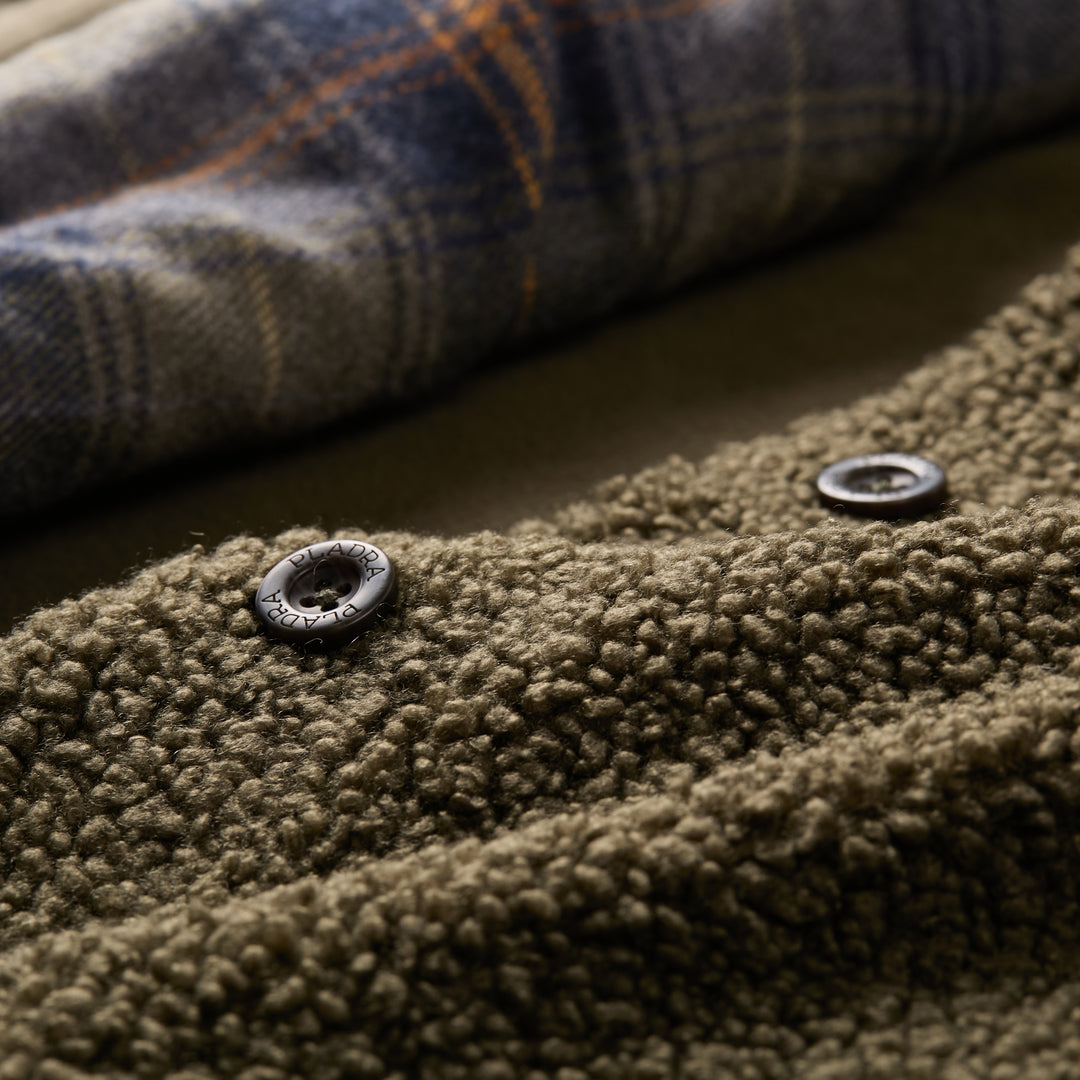 Close-up of Pladra Women's Headlands Sherpa Shacket in Forest Green, featuring black snaps and plaid flannel lining.