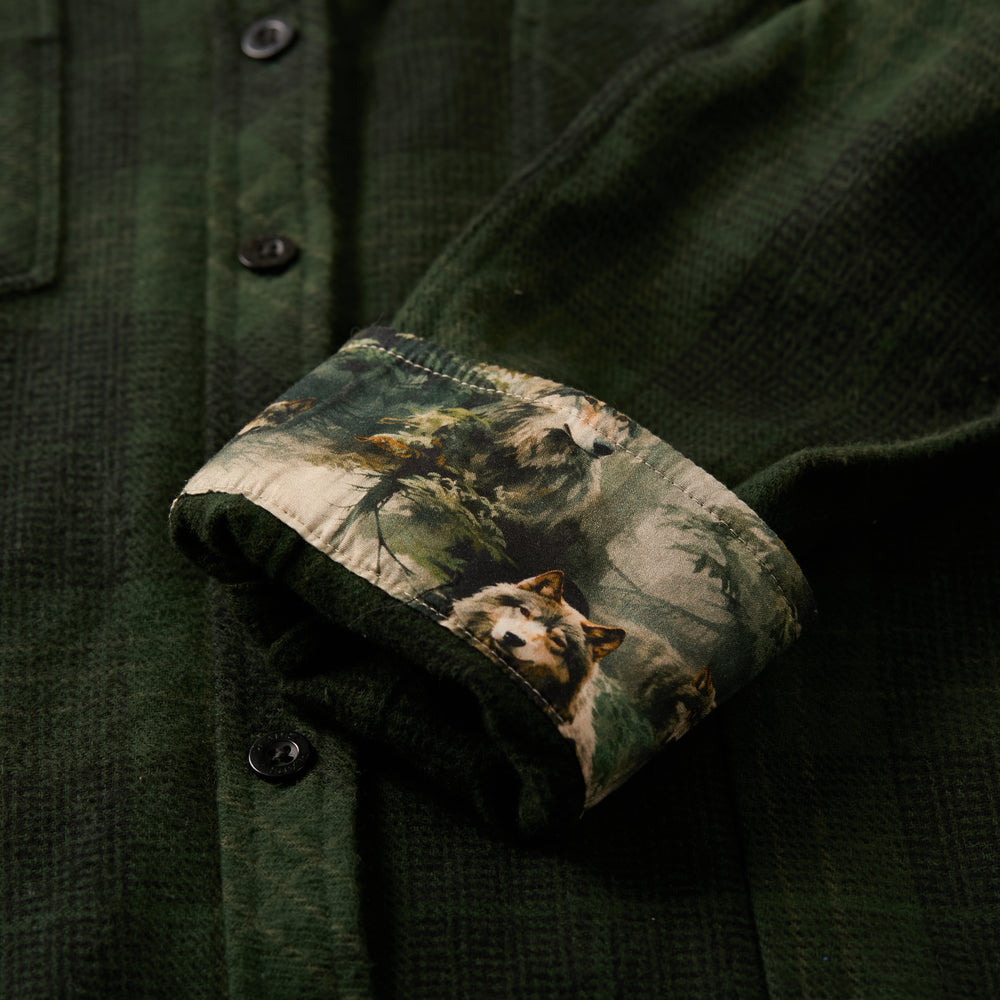 Close-up of Pladra Women's Every Day Elite Flannel Shirt in Humboldt Green with a cuff showing wolves in a forest scene.