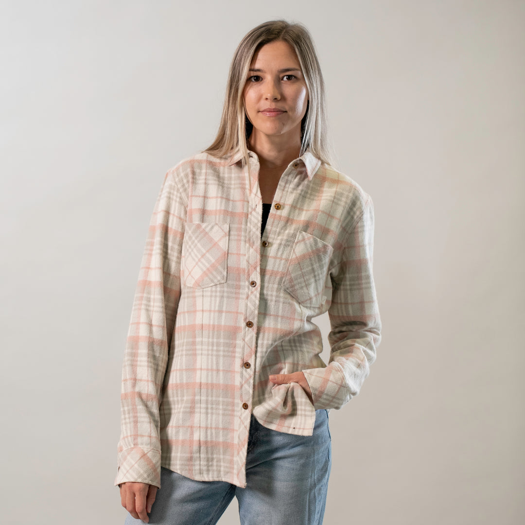 A woman wearing the Women's Every Day Elite Flannel Shirt in Lighthouse White and blue jeans stands with one hand in her pocket, facing the camera against a plain light background.