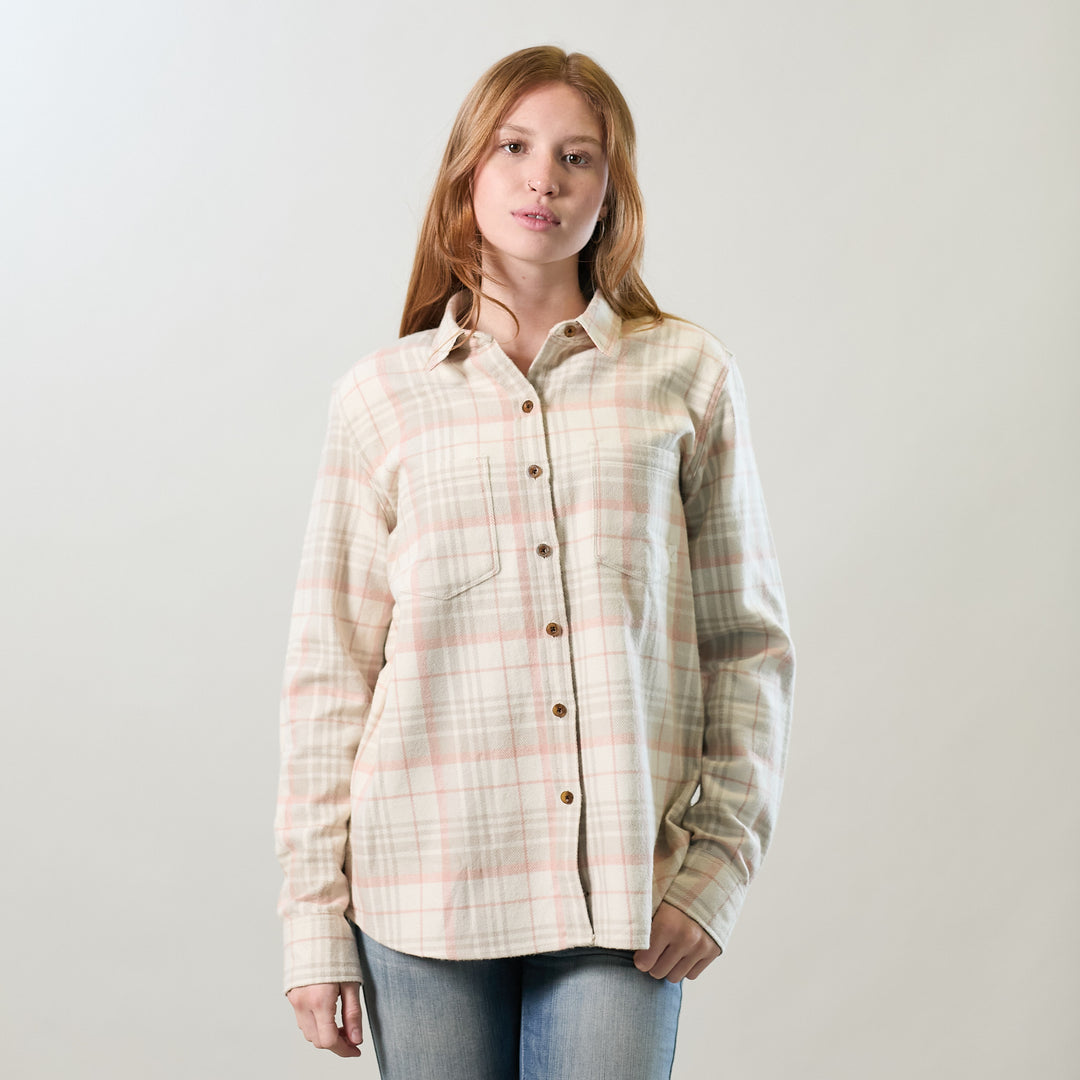 A woman with long, light brown hair wears the Women's Relaxed Every Day Elite Flannel Shirt in Lighthouse White and blue jeans, standing against a plain, light background.
