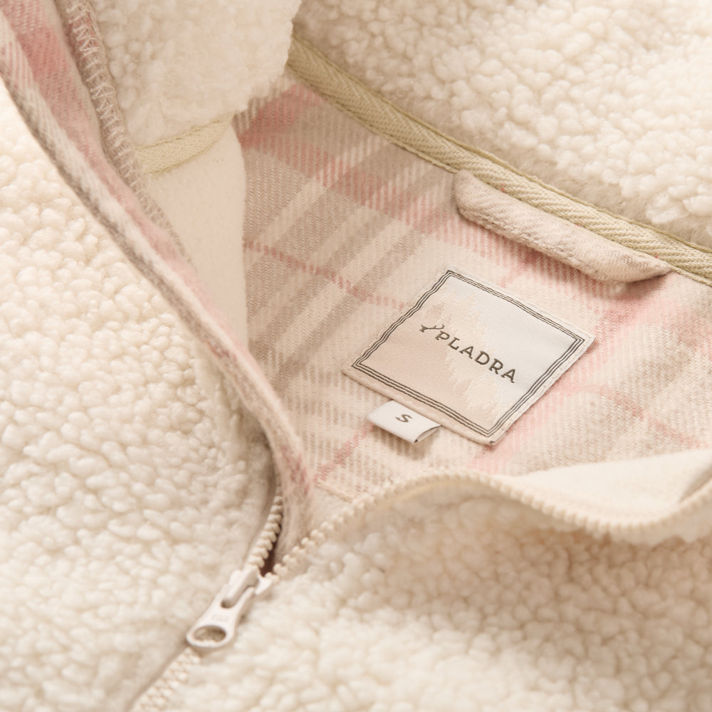 Close-up of Pladra Women's Jenner Sherpa Fleece in Oatmeal White, size S tag, with pink plaid flannel lining.