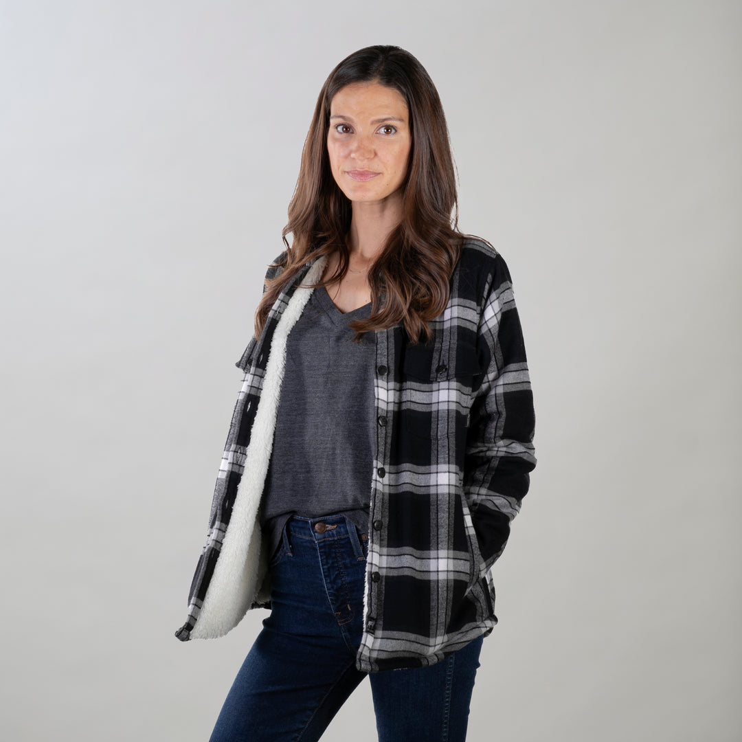 A woman with long brown hair wears the Pladra Women's Northwood Sherpa Insulated Flannel Jacket in RP Onyx Black.