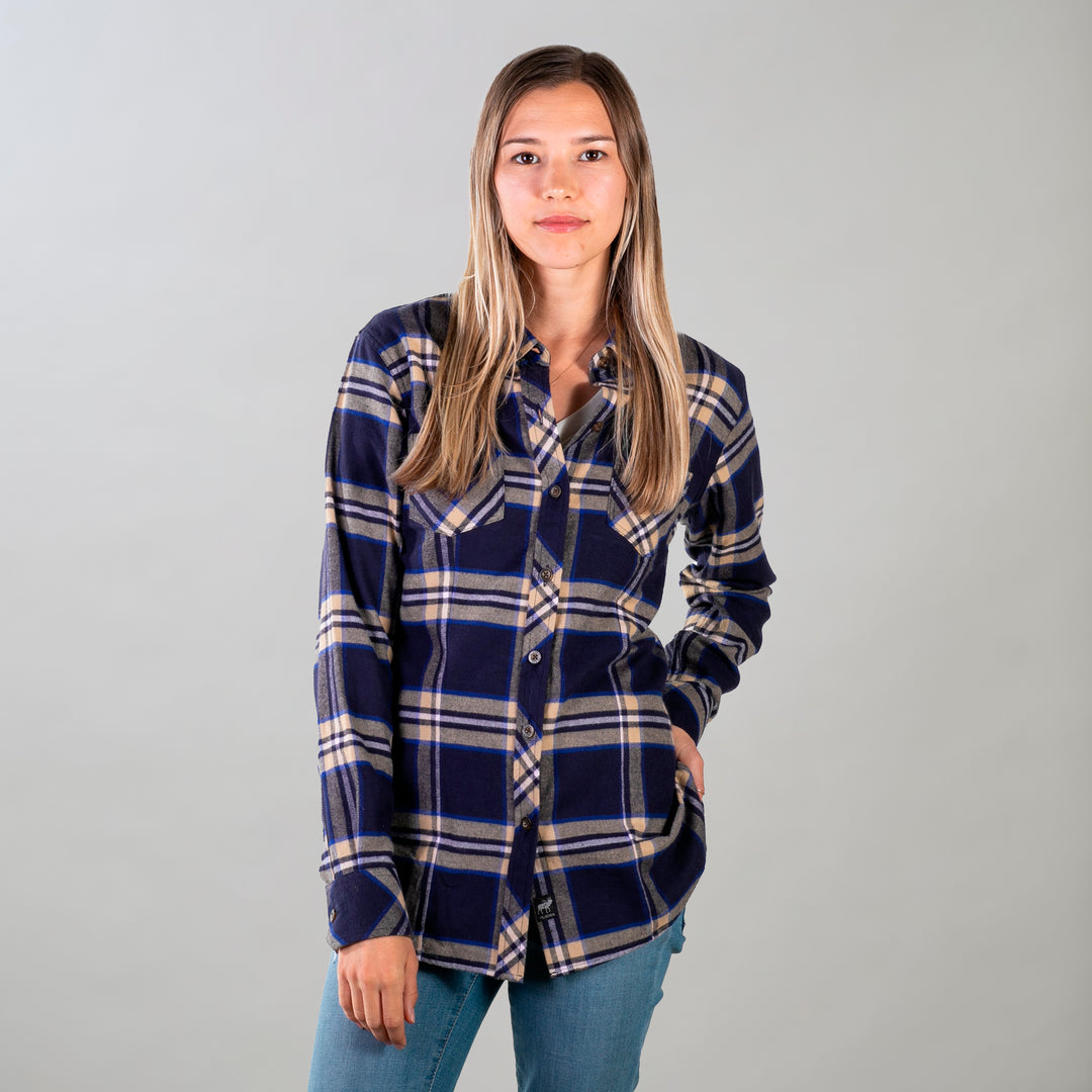 A woman with long, straight hair stands against a plain background, wearing the Women's Every Day Flannel Shirt in Slate Blue and light blue jeans. She looks at the camera with a neutral expression, one hand casually placed in her pocket.
