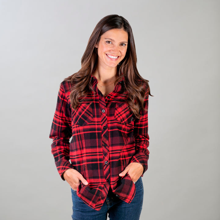 A woman with long brown hair smiles, hands in the pockets of the Women&
