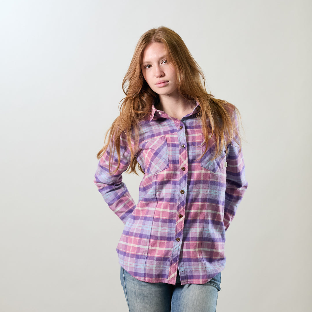 A young woman with long red hair wears a Pladra Women's Every Day Flannel Shirt in Wildflower Pink and jeans.