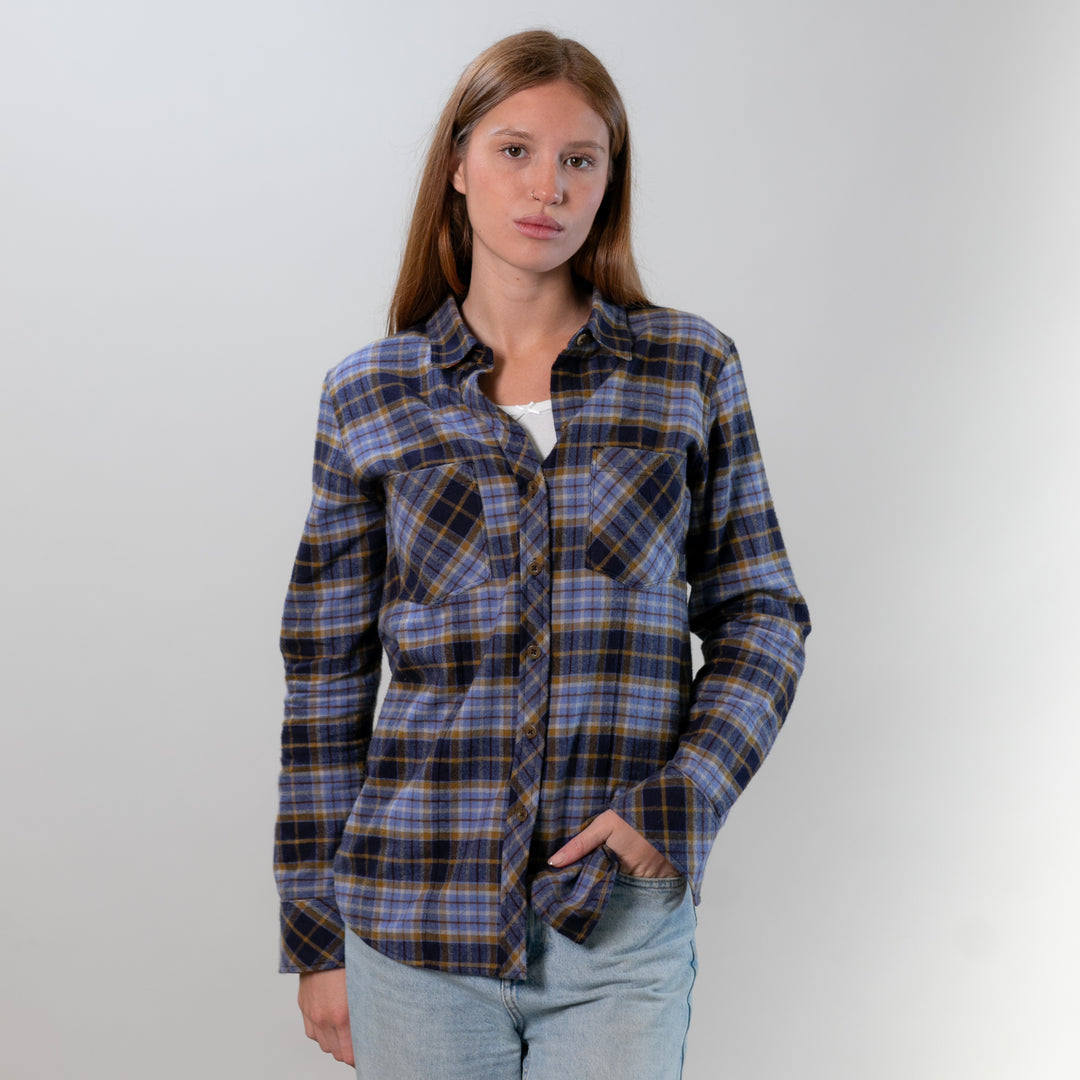 Person wearing a blue and brown plaid shirt against a plain background