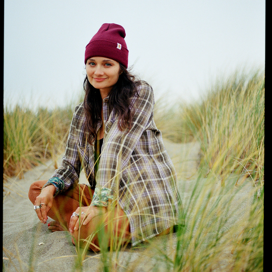 A woman in a maroon beanie, rings, and the Women&