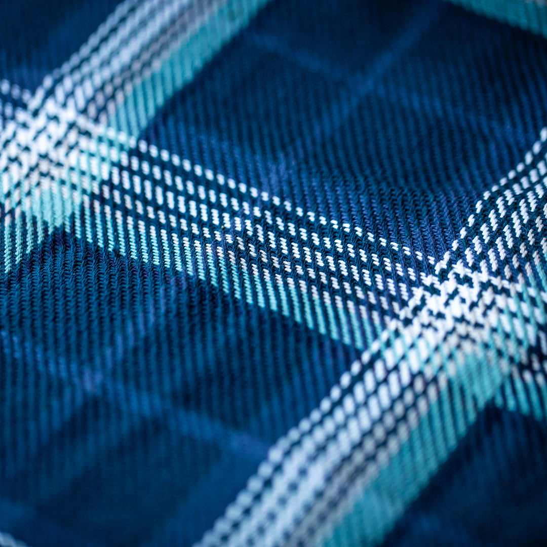 Close-up of Women's Fireside Flannel in Laguna Blue, featuring a blue and white plaid pattern on soft organic cotton with detailed woven texture and intersecting lines in shades of blue, white, and teal.