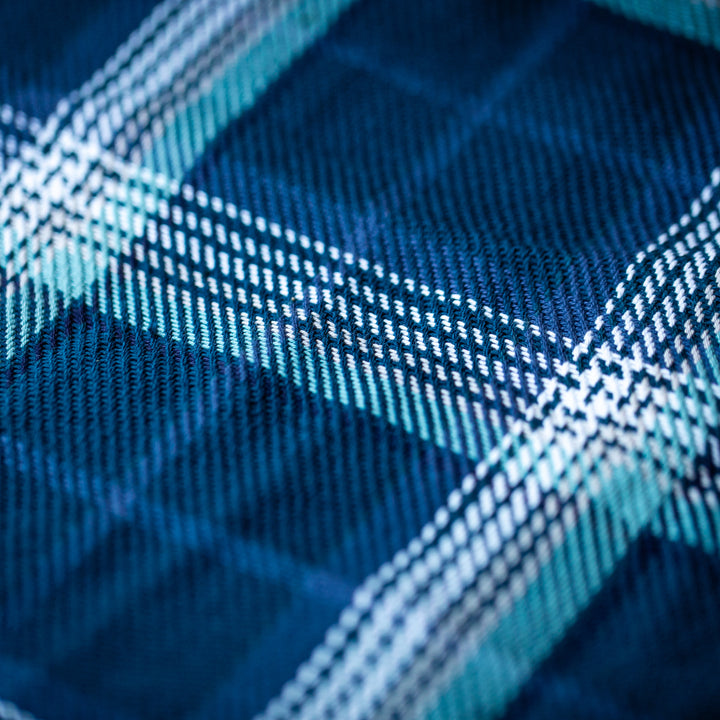 Close-up of Women's Fireside Flannel in Laguna Blue, featuring a blue and white plaid pattern on soft organic cotton with detailed woven texture and intersecting lines in shades of blue, white, and teal.