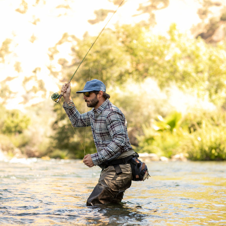 Man fly fishing in a river, wearing Pladra Men&