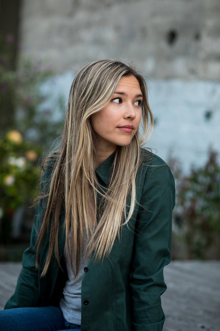 A young woman sits outdoors in a Pladra Women&