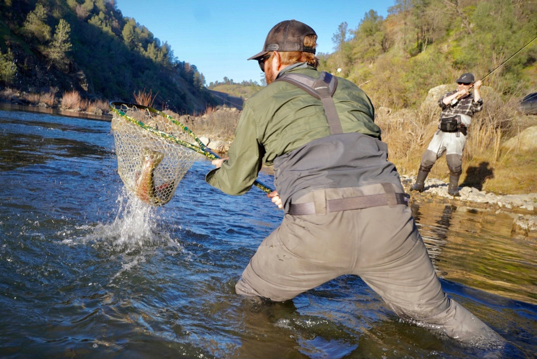 Two anglers fish; one nets a catch, the other sports Pladra’s Men&