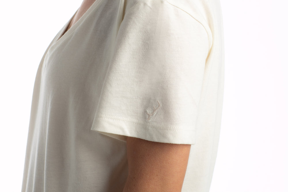 Model in Pladra Women’s V-Neck Tri-Blend Tee—Marshmallow White Heather, side view, logo on sleeve.